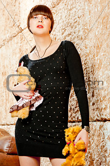 Girl with bangs in a black dress posing with teddy bears