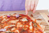 hand making fresh pizza on wooden board