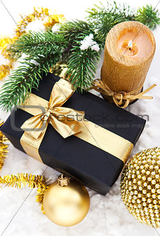 Golden Christmas composition with gift box, candle and branch of