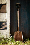 Old Vintage Metal Shovel with rust on blue barn Door.