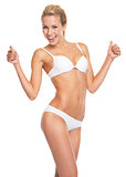 Happy young woman in lingerie showing thumbs up