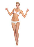 Full length portrait of happy young woman in lingerie showing th