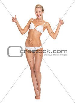 Full length portrait of happy young woman in lingerie showing th