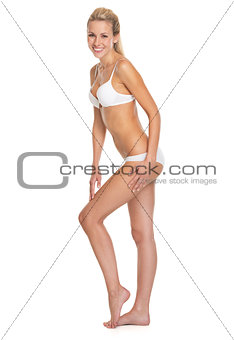 Full length portrait of smiling young woman in lingerie touching
