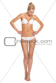 Full length portrait of young woman in lingerie looking on belly