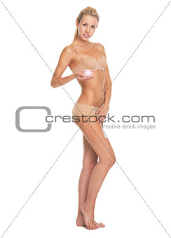 Full length portrait of young woman in lingerie applying creme o