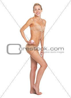 Full length portrait of smiling young woman in lingerie applying