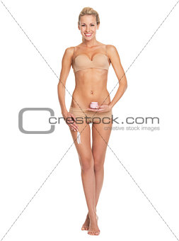 Full length portrait of happy young woman in lingerie applying c