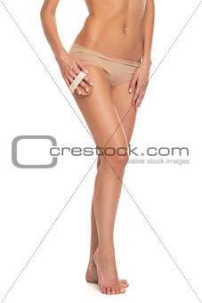Closeup on young woman in lingerie using massager on leg