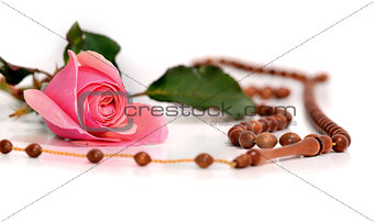 Muslim rosary and pink rose on a white background