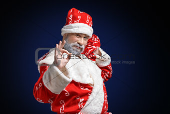 Santa Claus shows OK sign on a dark background