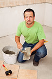Worker laying ceramic floor tiles