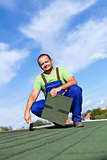 Worker installs bitumen roof shingles