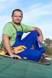 Worker laying bitumen roof shingles