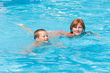 Mother train her son to swim in the pool.