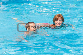 Mother train her son to swim in the pool.