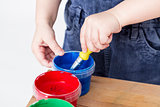 child holding brush in paint tub