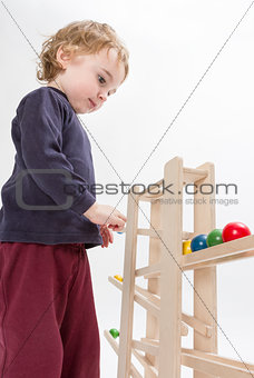 child playing with wooden ball path
