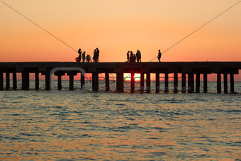 People on the old sea pier during sunset