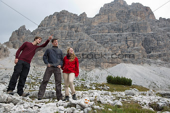 Young man showing his group the destination in the mountains