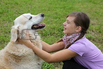Child embracing dog on a meadow
