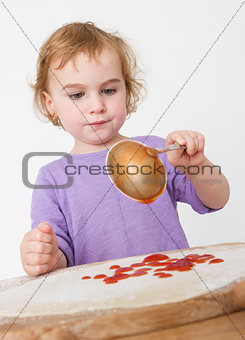 child putting sieved tomatoes on dough