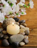 still life a lit candle and stones on wooden background