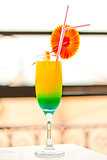 bright alcoholic cocktail in a glass with decorations on the edge of the table