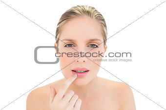 Confused fresh blonde woman touching her lip