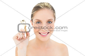 Cheerful fresh blonde woman holding an eyelash curler