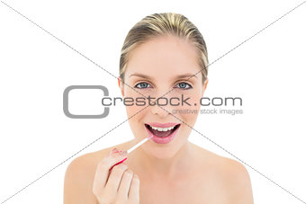 Joyful fresh blonde woman applying gloss