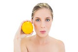 Attractive fresh blonde woman pouting and holding an orange