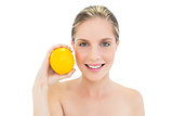 Smiling fresh blonde woman holding an orange