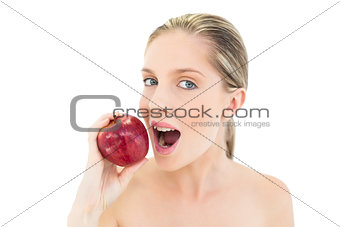Cute fresh blonde woman eating a red apple