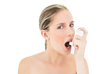Natural fresh blonde woman using asthma inhaler
