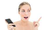 Shocked fresh blonde woman holding a mobile phone and raising her finger
