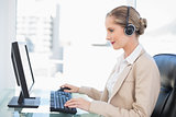 Smiling blonde call centre agent working on computer