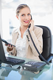 Smiling blonde businesswoman on the phone holding calculator