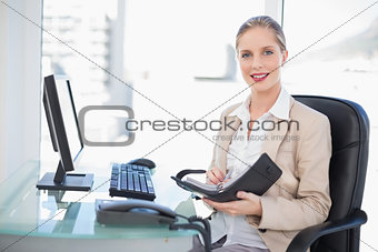 Happy blonde businesswoman holding datebook