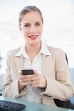 Smiling blonde businesswoman text messaging