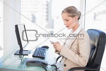 Focused blonde businesswoman text messaging