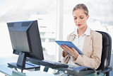 Concentrated blonde businesswoman using tablet