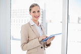 Cheerful blonde businesswoman using tablet pc