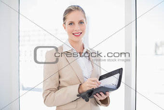 Smiling blonde businesswoman holding datebook standing