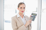 Serious blonde businesswoman showing calculator