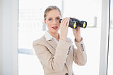 Peaceful blonde businesswoman holding binoculars