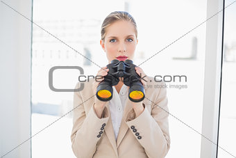 Serious blonde businesswoman holding binoculars