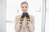 Smiling blonde businesswoman holding binoculars