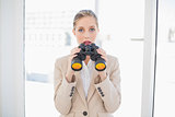 Astonished blonde businesswoman holding binoculars