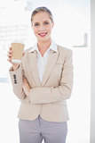 Smiling blonde businesswoman holding coffee